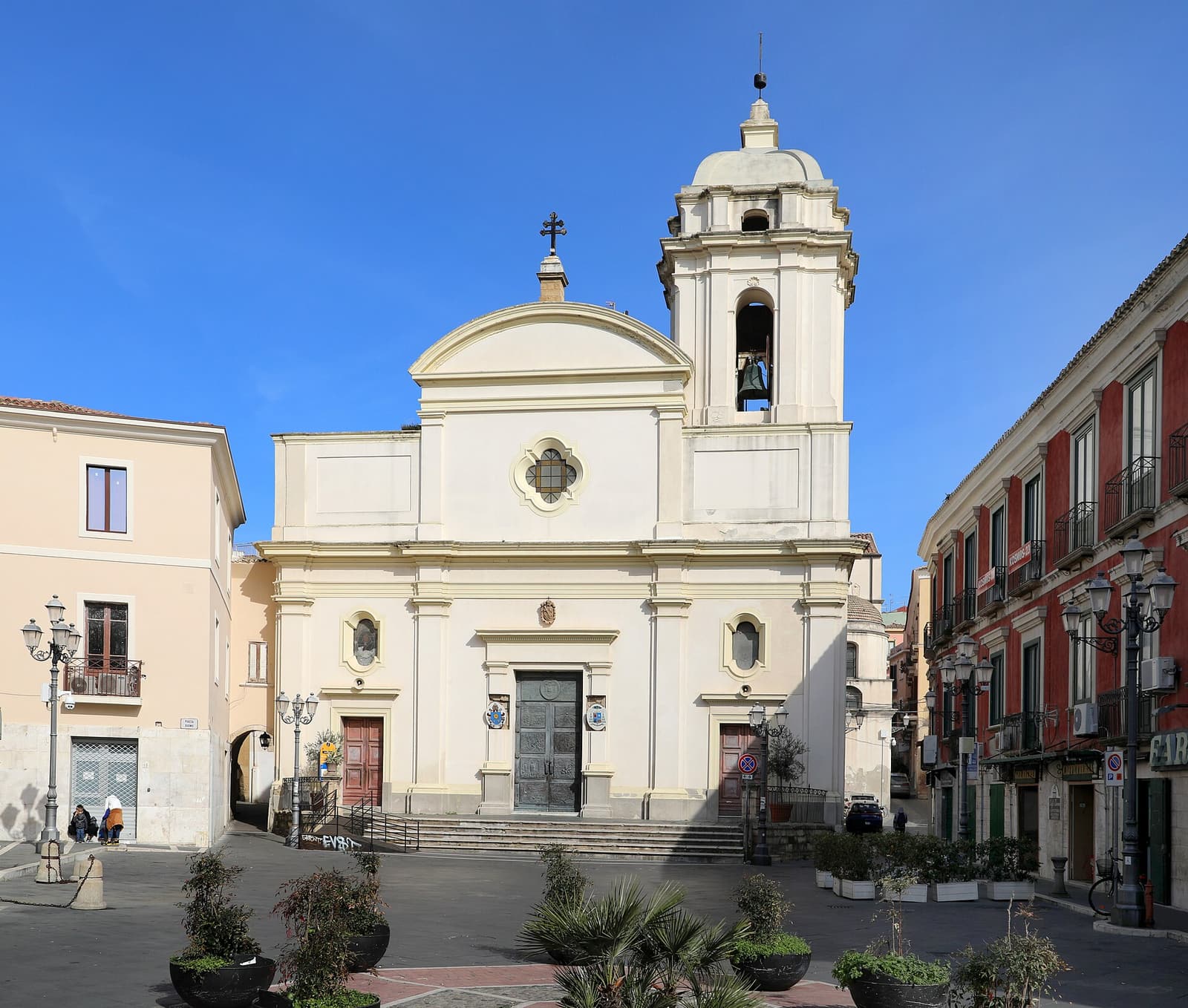 The pale neoclassical facade and bell tower of Crotone Cathedral on Piazza Duomo